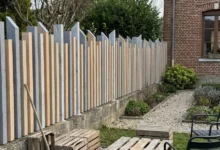 clôture à lames verticales ajourées prés d'une maison en briques