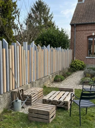 clôture à lames verticales ajourées prés d'une maison en briques