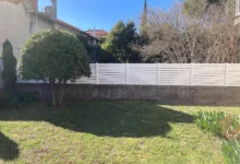 Clôture occultante en pvc blanche installée sur un vieux muret