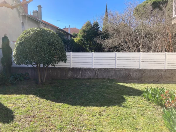 Clôture occultante en pvc blanche installée sur un vieux muret
