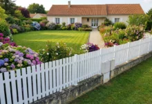 clôture ajourée posée sur un muret ancien autour d'un jardin fleuri