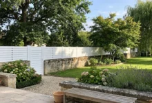 clôture brise vue posée sur un vieux muret en pierres dans le jardin d'un domaine champêtre