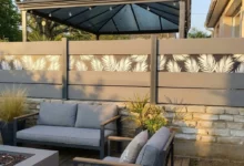 clôture grise à lames larges avec une impression personnalisée installée sur un muret en pierres