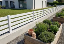 clôture ajourée blanche entourant une maison neuve prés d'un potager