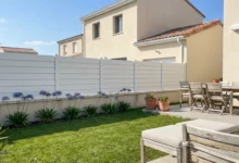 clôture blanche moderne dans un jardin de maison contemporaine avec terrasse et mobilier extérieur en bois