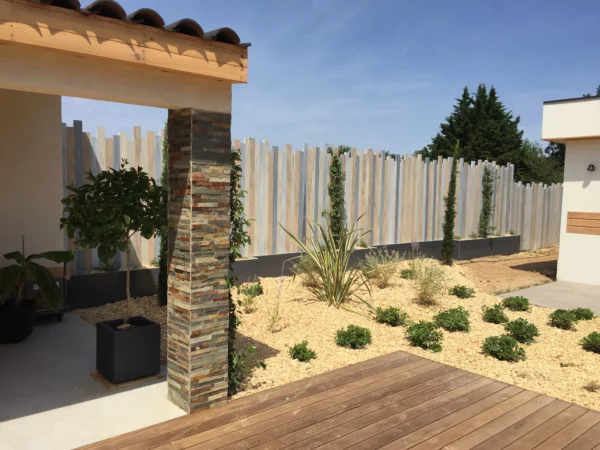 Clôture brise-vue PVC modèle Iliade à lames verticales de hauteurs irrégulières, dans un jardin minéral contemporain