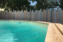 Clôture brise-vue modèle Iliade autour d’une piscine, avec lames verticales de hauteurs variées pour préserver l’intimité