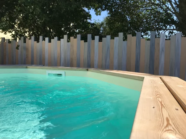 Clôture brise-vue modèle Iliade autour d’une piscine, avec lames verticales de hauteurs variées pour préserver l’intimité