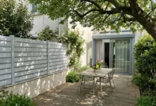 clôture de teinte gris clair posée sur un petit muret crépis mitoyen entre deux voisins