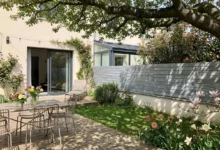 clôture grise qui délimite un jardin posée sur un muret surmonté d'une couvertine béton