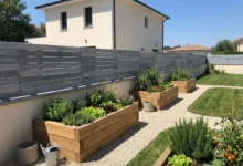 Clôture sans poteau ajourée grise installée sur un muret prés de carrés potager