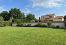 clôture en composite effet bois avec des liserés entre les lames gris anthracite posée sur un muret enduit dans un jardin résidentiel