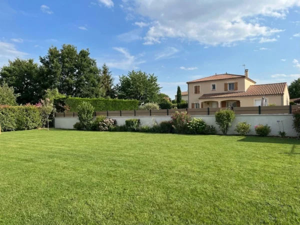 clôture en composite effet bois avec des liserés entre les lames gris anthracite posée sur un muret enduit dans un jardin résidentiel