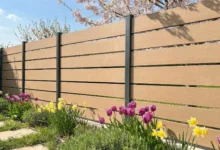 clôture imitation bois moderne avec poteaux anthracite, installée dans un jardin fleuri