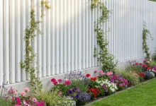 Clôture blanche à lames verticales sans poteaux prés de massifs fleuris