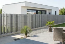 Clôture droite à lames verticales installée sur un soubassement en béton autour d'une villa contemporaine