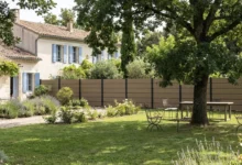 clôture en composite brise vue effet bois posée près d'une maison en pierre