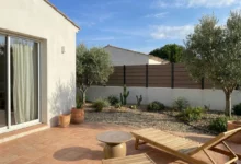Clôture beige avec poteaux gris foncé installée sur un muret enduit