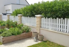 Clôture mitoyenne à lames verticales ajourée posée entre piliers béton