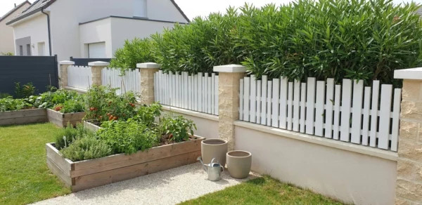 Clôture mitoyenne à lames verticales ajourée posée entre piliers béton