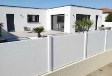 clôture pleine blanche fixée sur un muret en parpaings enduit autour d'une maison neuve