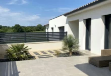 clôture moderne foncée installée sur un muret enduit autour d'une terrasse dans un environnement contemporain