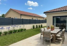 clôture style persienne posée sur un muret enduit autour d'une maison récente