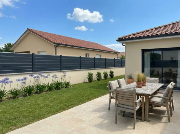 clôture style persienne posée sur un muret enduit autour d'une maison récente