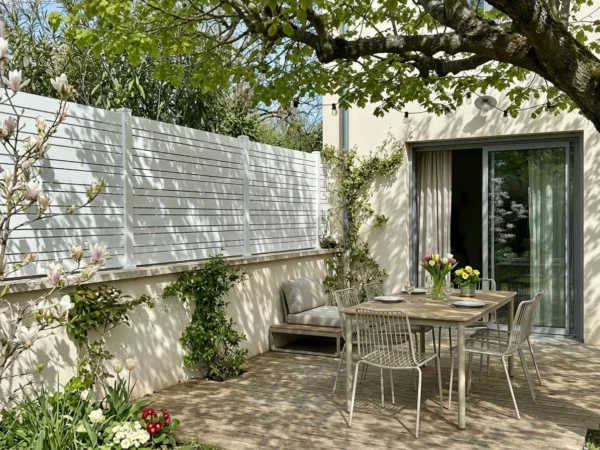 clôture blanche installée sur un muret sur couvertine en béton dans un jardin bucolique