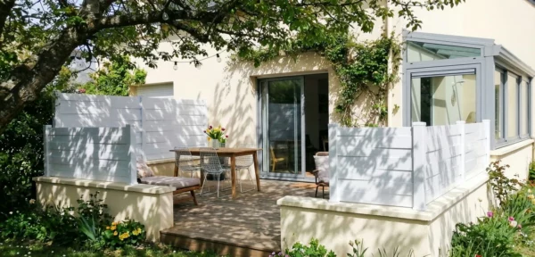 clôture blanche originale posée sur une murette enduit autour d'un terrasse en bois