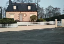 clôture ajourée à lames verticales installée sur un petit muret en pente