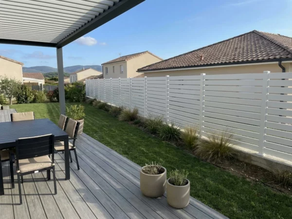 clôture PVC ajourée blanche dans le jardin d'une maison de lotissement récente