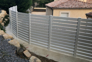 Clôture en pvc blanc ajouré installée sur muret en courbe avec un espacement de 20 mm entre chaque lames horizontales