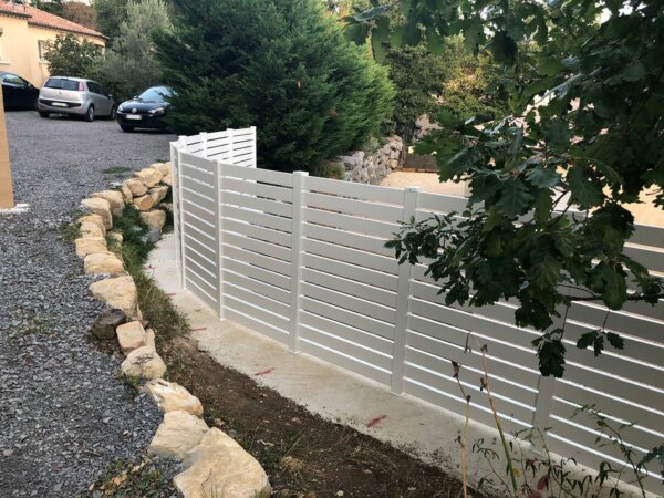 Clôture en pvc blanc ajouré installée sur muret en courbe avec un espacement de 20 mm entre chaque lames horizontales