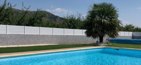 Au bord d'une piscine aménagement d'une clôture en pvc blanc ajouré avec un espacement de 10 mm entre chaque lames horizontales