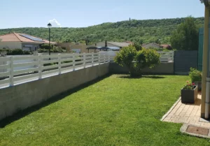 Clôture en pvc blanc ajourée installée sur muret pour sublimer votre jardin.