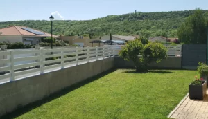 Clôture en pvc blanc ajourée installée sur muret pour sublimer votre jardin.