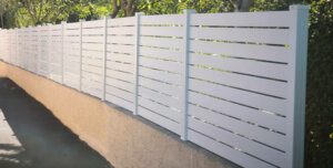 Clôture en pvc blanc ajouré installée sur muret avec un espacement de 20 mm entre chaque lames horizontales