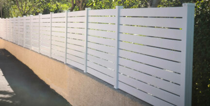 Clôture en pvc blanc ajouré installée sur muret avec un espacement de 20 mm entre chaque lames horizontales