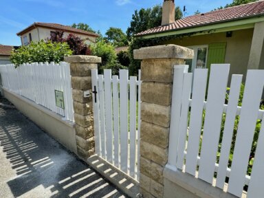 Clôture en pvc blanc ajourée installée avec une variation subtile des largeurs de lames avec portail et portillon assortis