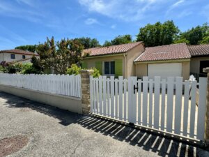 Clôture en pvc blanc ajourée installée avec une variation subtile des largeurs de lames avec portail et portillon assortis