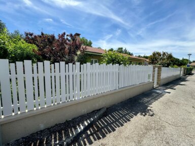 Clôture en pvc blanc ajourée installée avec une variation subtile des largeurs de lames avec portail et portillon assortis