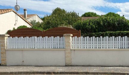 Clôture en pvc blanc ajourée installée avec une variation subtile des largeurs de lames