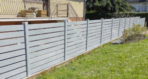 Clôture en pvc gris ajouré installée sur muret avec un espacement de 20 mm entre chaque lames horizontales