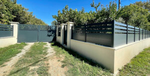 Clôture en pvc plaxé gris anthracite ajouré installée sur muret avec un joli portail assorti