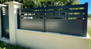 Clôture en pvc plaxé gris anthracite ajouré installée sur muret avec un espacement de 100 mm entre chaque lames horizontales