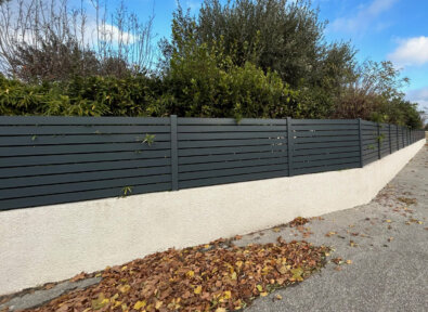 Clôture Fusion en PVC plaxé couleur gris anthracite et un espacement entre lames de 10 mm, installée sur un muret.