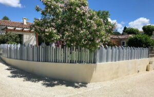Clôture en pvc gris ajourée en arrondi installée sur muret pour apporter une touche d'originalité à votre propriété
