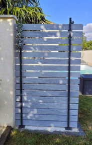 Clôture en pvc gris ajourée installée pour une petite séparation dans un jardin
