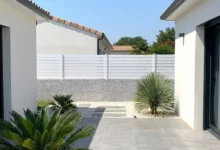 clôture ajourée de 1cm entre les lames en PVC blanc prés d'une maison contemporaine